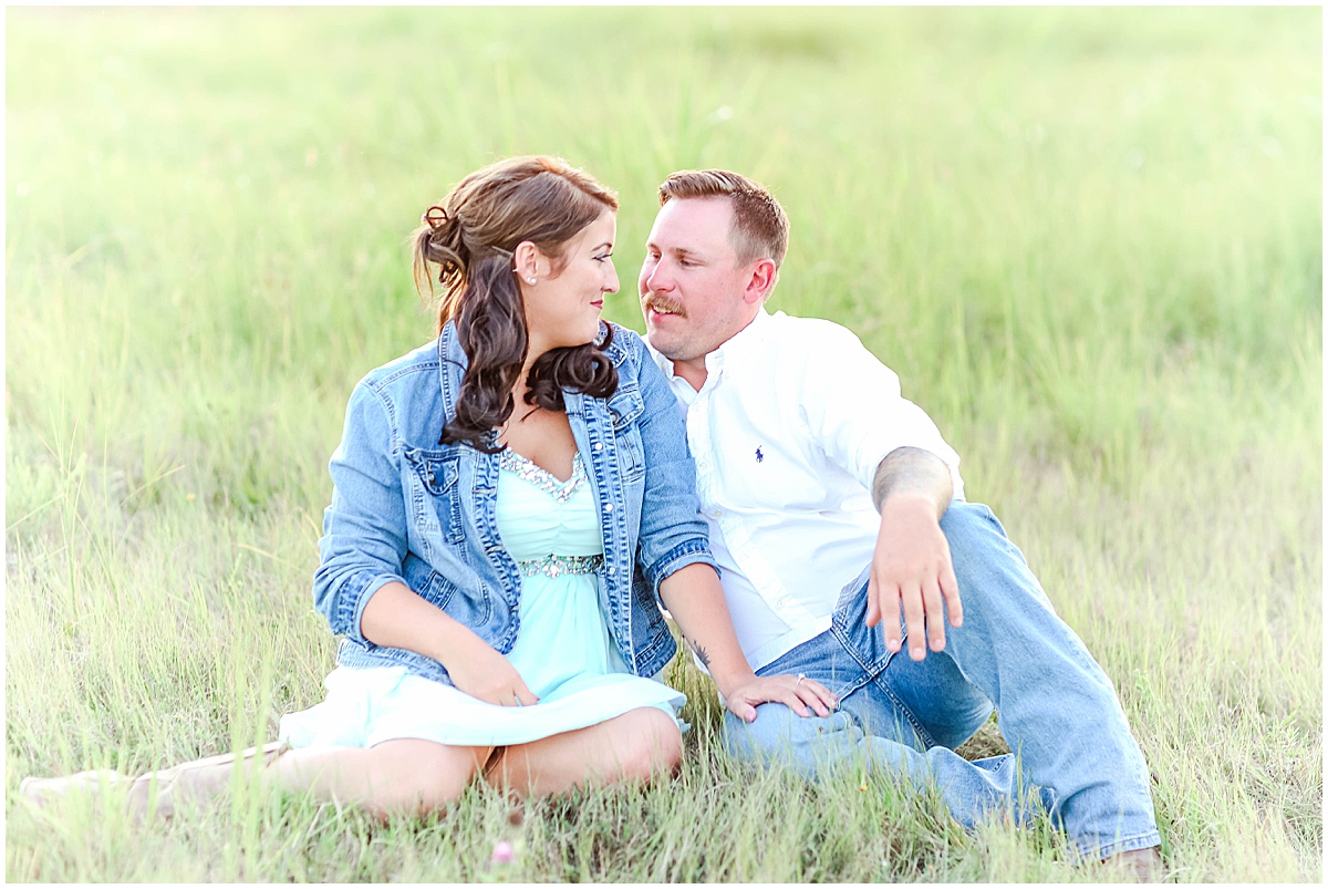 couple sitting in field at engagement session